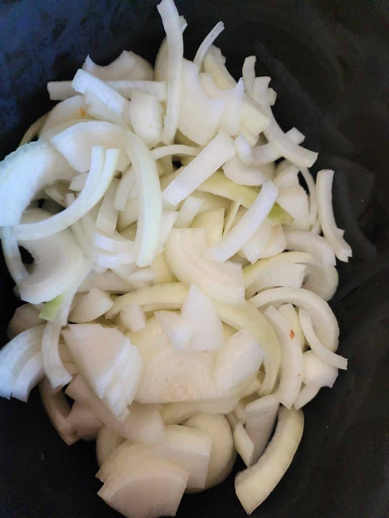 Onions added to a crock pot to make and can caramelized onions