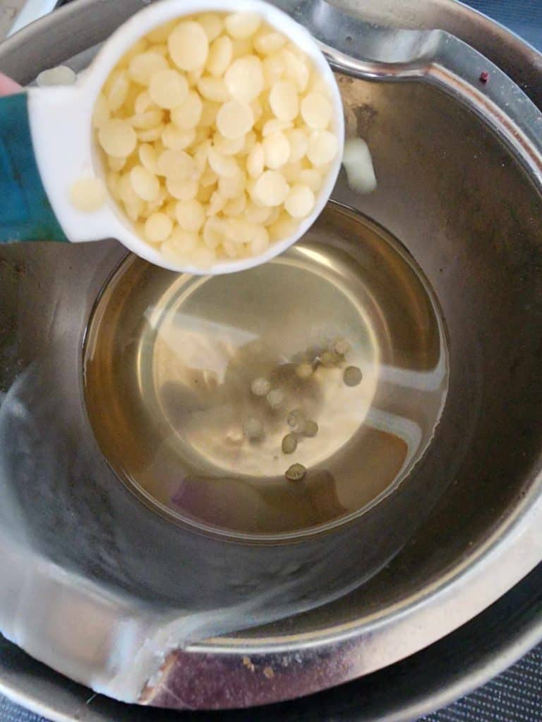 adding beeswax pellets to rosemary infused oil to make rosemary salve