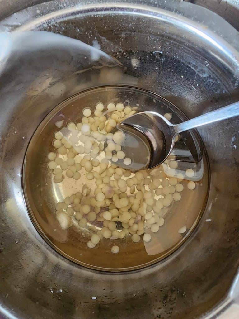 stirring the beeswax pellets and shea butter into the rosemary infused oil to make rosemary salve