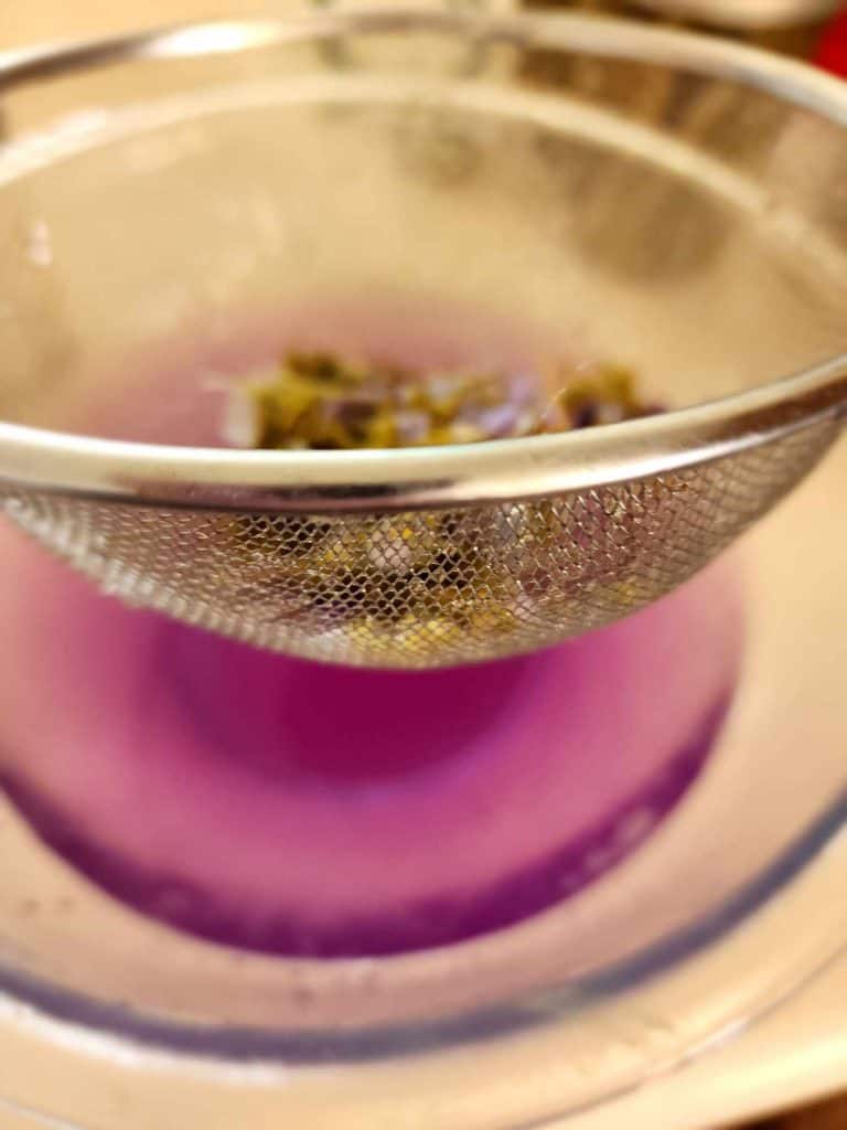 straining violet tea from the violets to make violet jelly