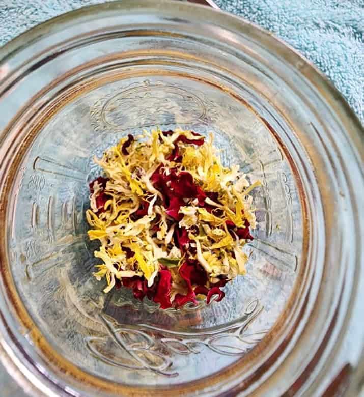 dried honeysuckle and rose flowers in a mason jar to make honeysuckle rose lotion bars