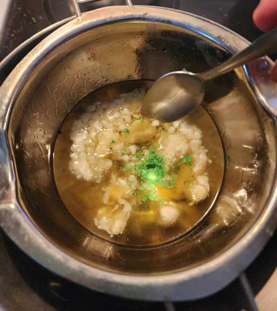 Stirring beeswax and shea butter into infused oil for catnip lotion bars