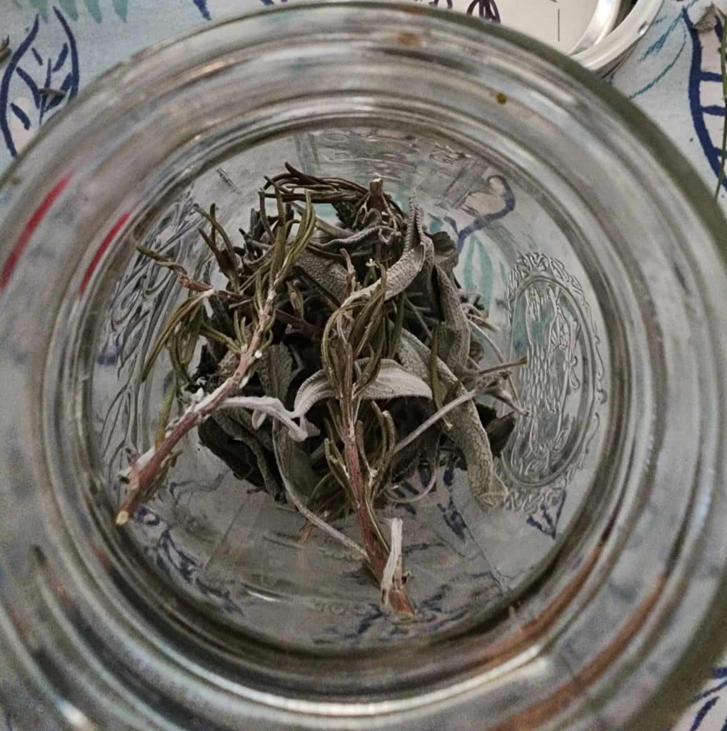 sage and rosemary dried leaves in a mason jar for sage and rosemary lotion bar recipe