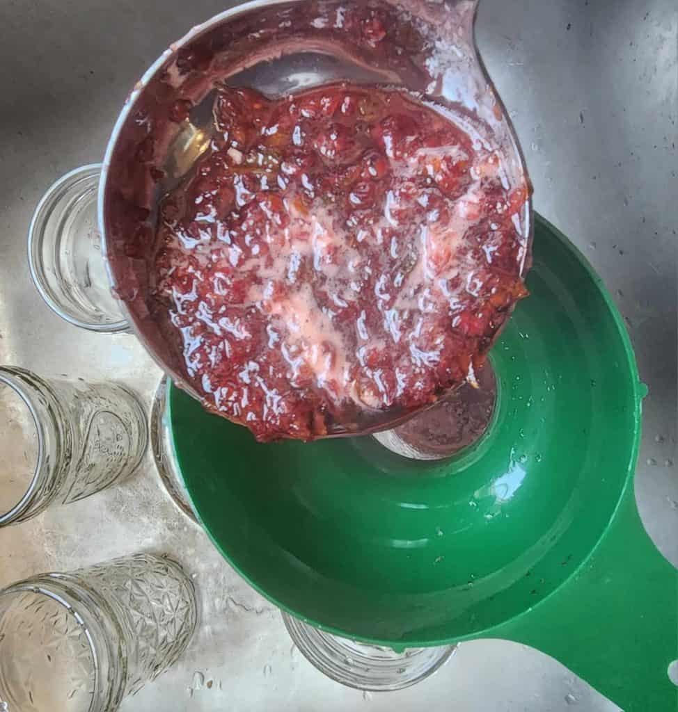 ladling cherry jalapeno jelly into the jars