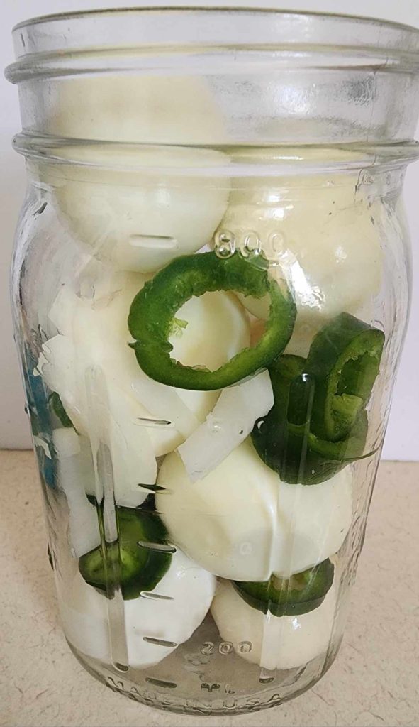 hard boiled eggs, jalapenos and onions in the jar for pickled jalapeno eggs