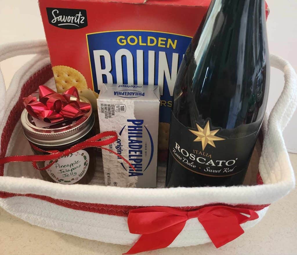 Jalapeno jelly in Christmas basket with cream cheese, crackers and a bottle of wine