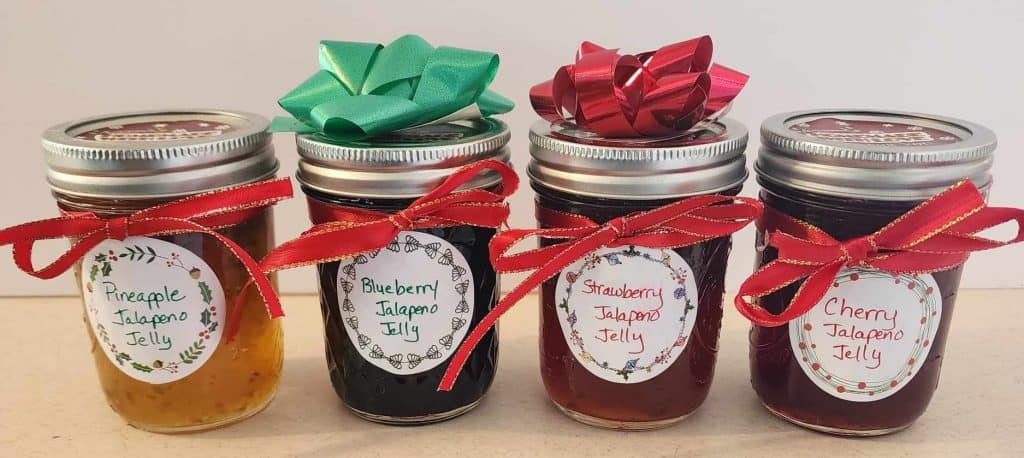 Four different kinds of jalapeno jellies decorated as Christmas gifts