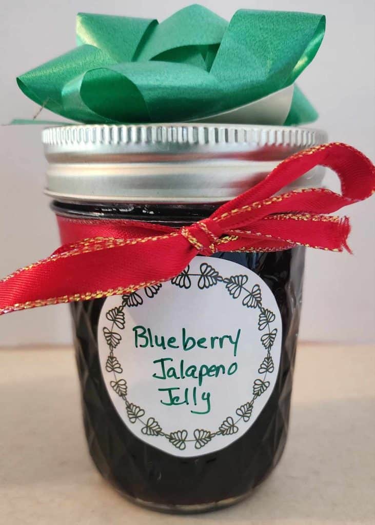 Jar of blueberry jalapeno jelly decorated with bow and ribbon for Christmas gift