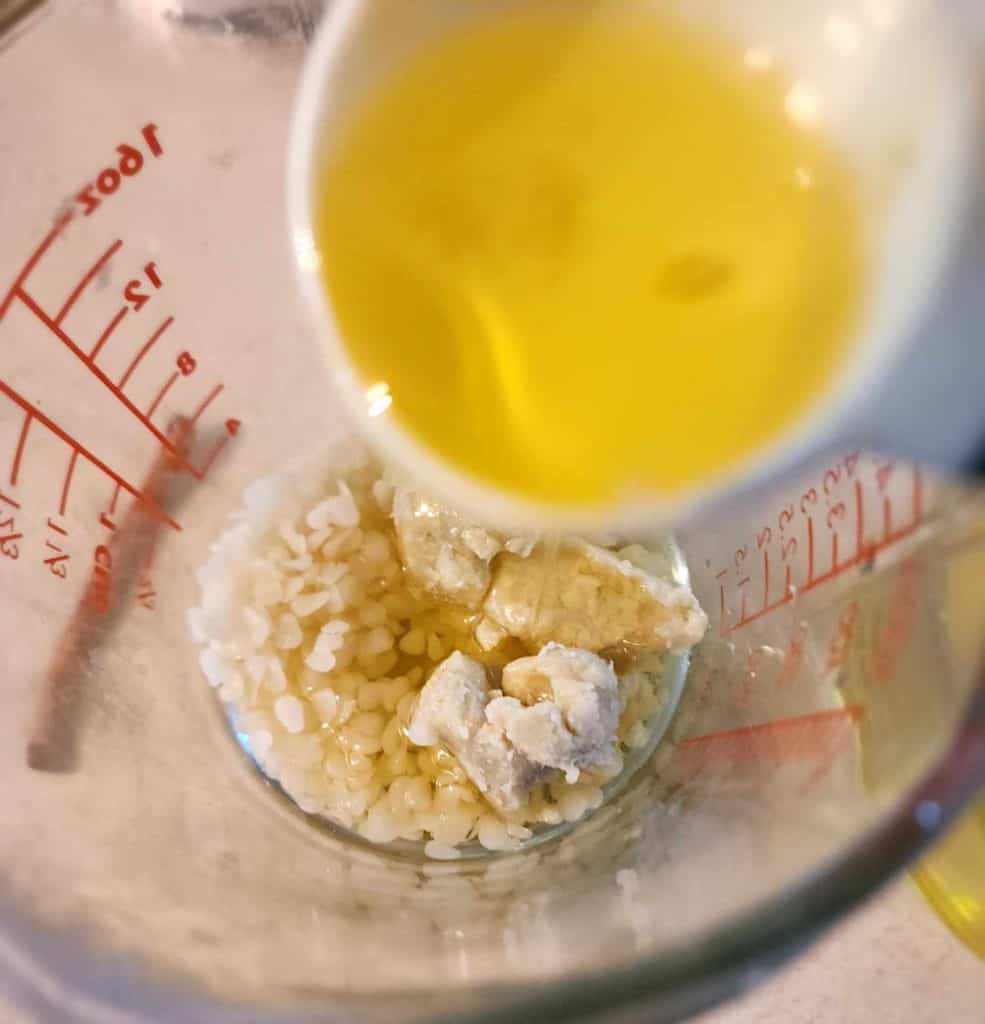 Adding calendula infused oil to the rest of the ingredients for calendula lip balm recipe