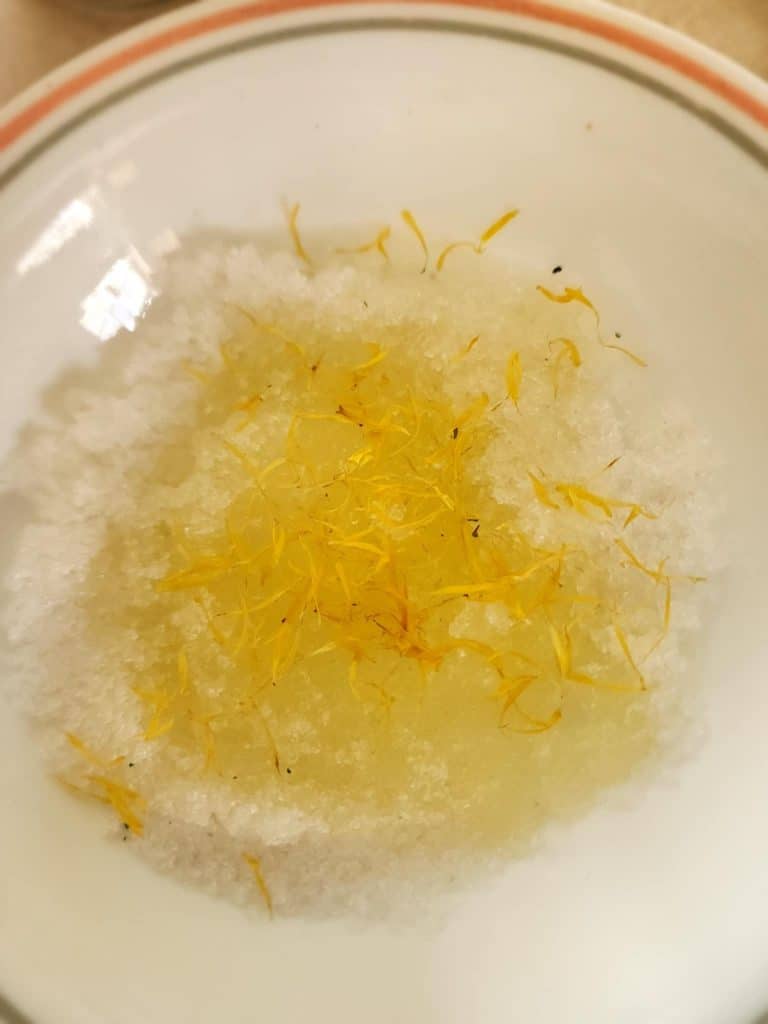 calendula salt scrub ingredients added to a bowl