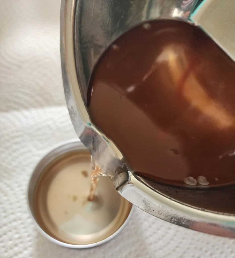 pouring liquid rose salve into tins