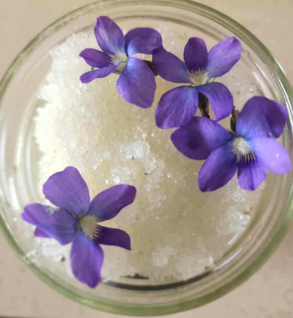 violet salt scrub in a jar with flowers