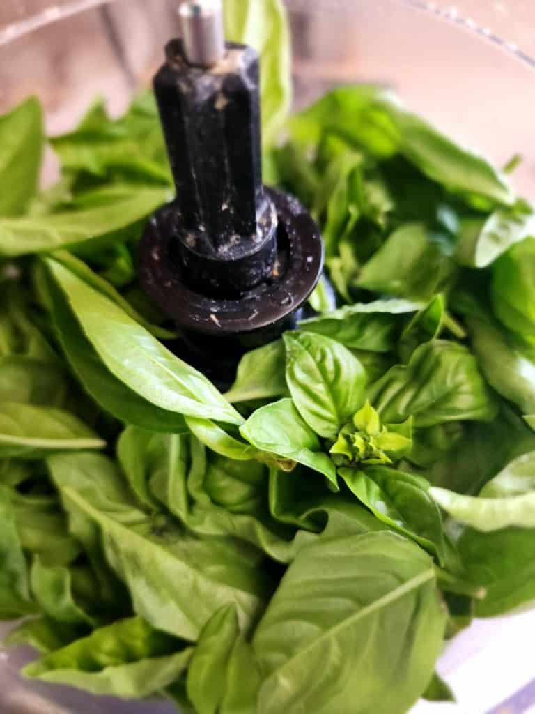 Adding basil to the food processor to make basil pesto
