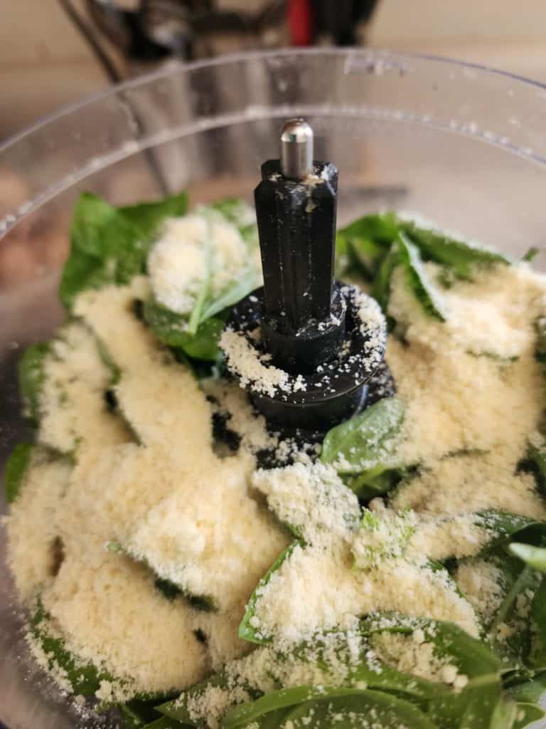 Adding ingredients to food processor to make basil pesto