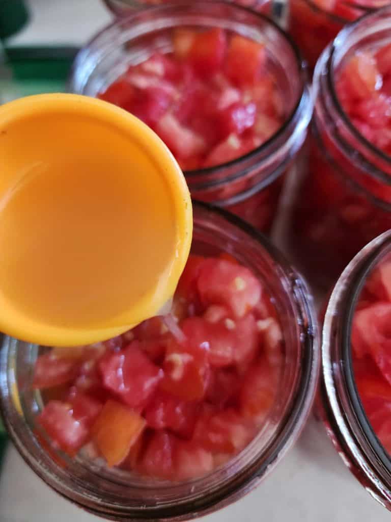 adding lemon juice to jars of diced tomatoes