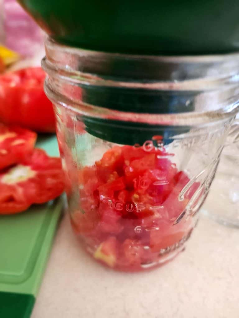 putting diced tomatoes in the canning jar using a canning funnel