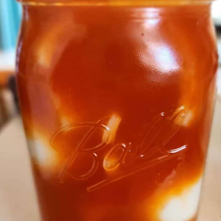 jar of eggs with sriracha brine poured over before putting in refrigerator