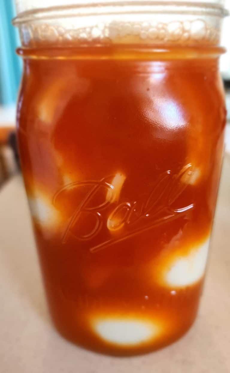 jar of eggs with sriracha brine poured over before putting in refrigerator