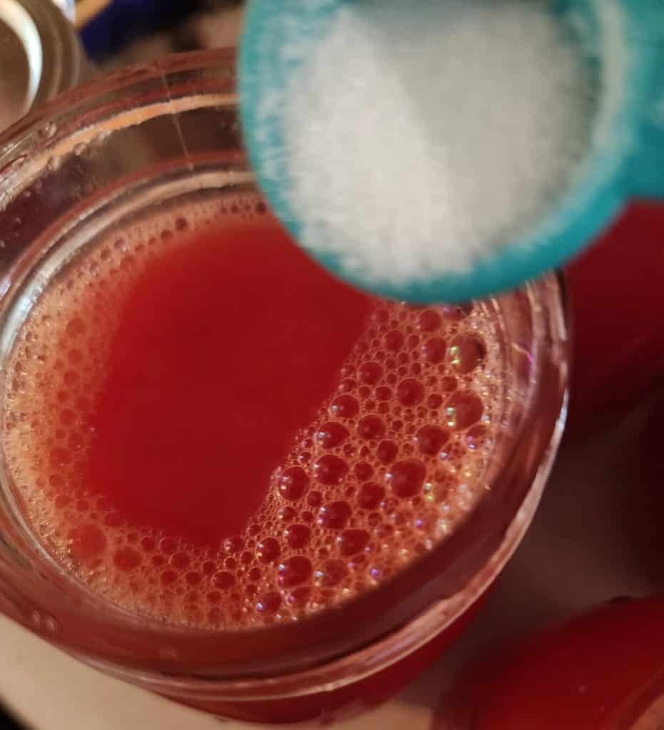 adding salt to each jar of tomato juice