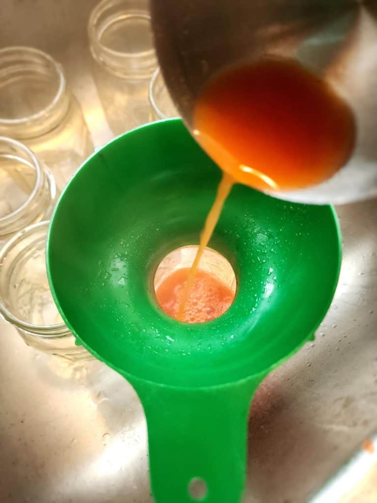 ladling tomato juice into jars for canning