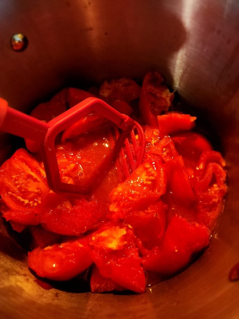 Mashing tomatoes with potato masher for tomato juice