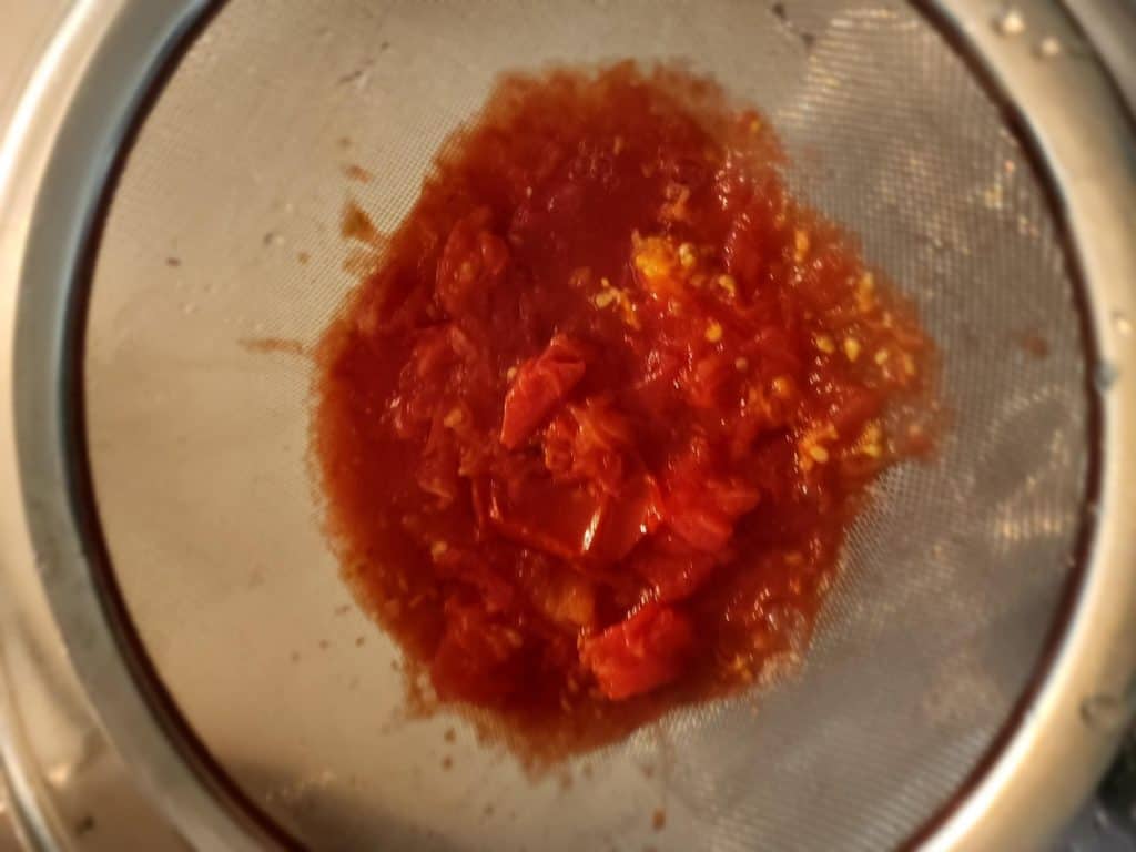 adding tomatoes to strainer