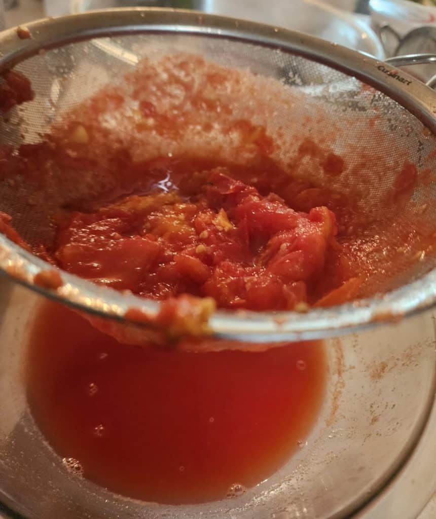 straining tomatoes to make tomato juice