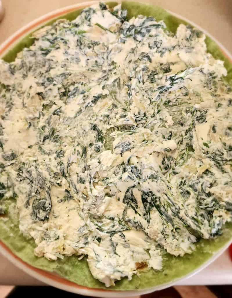 spinach dip spread on tortilla for spinach dip rollup