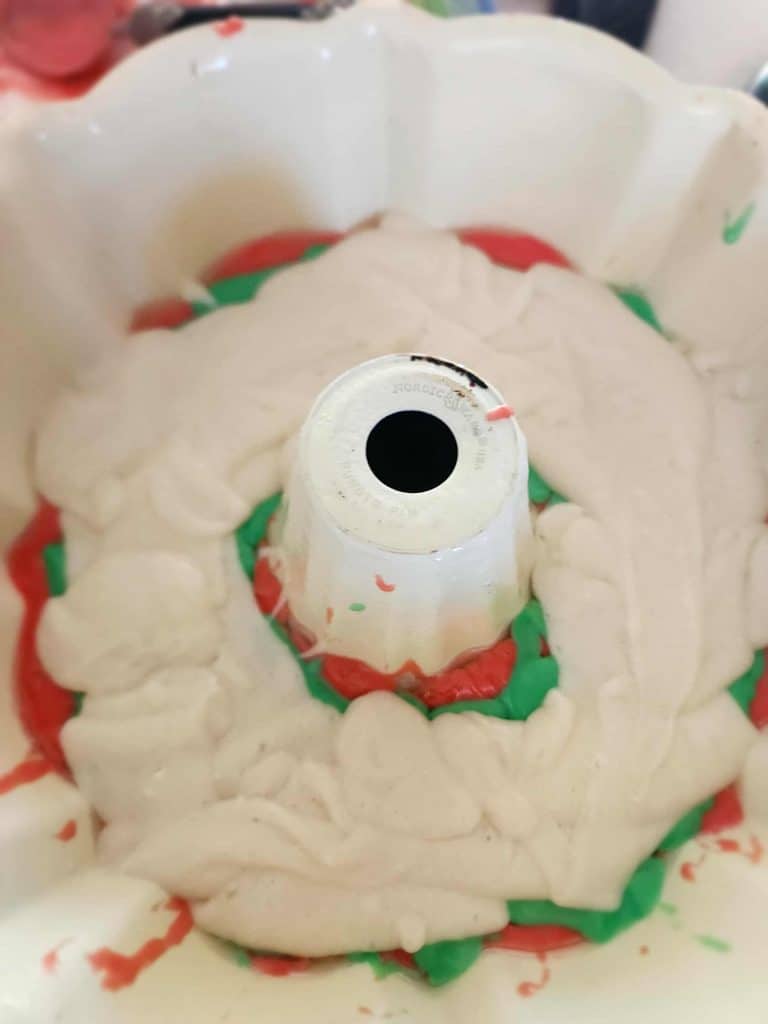 layering red, green and white cake batter in the bundt cake for Christmas bundt cake