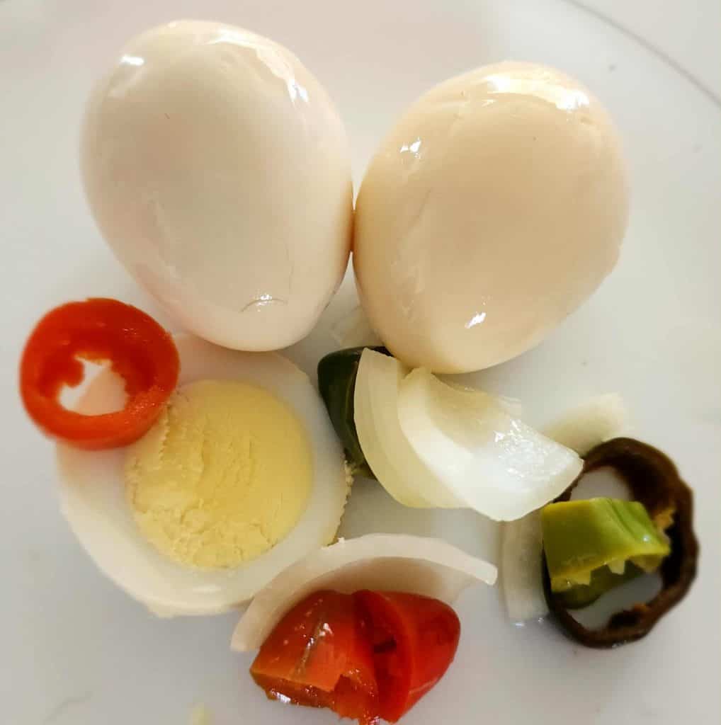 Sweet and Spicy pickled egg with slice and peppers and onions.