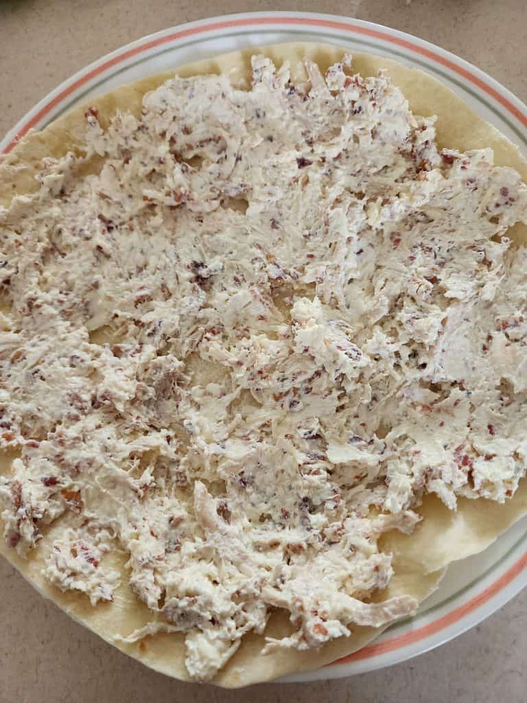 Caesar chicken cream cheese mixture spread on tortilla for caesar chicken roll ups