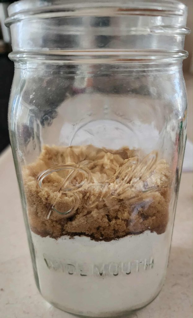 Brown sugar added to quart mason jar to make Christmas muffins in a jar