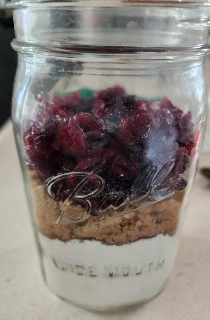 Cranberried added to mason jar to make Christmas muffins in a jar