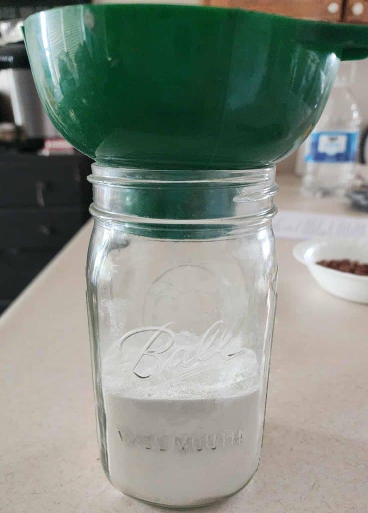 Flour added to jar with a canning funnel to make Christmas Muffins in a Jar