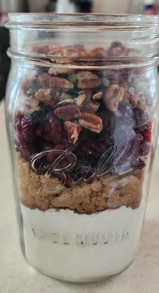 Ingredients for Christmas muffins in a jar layered in quart mason jar