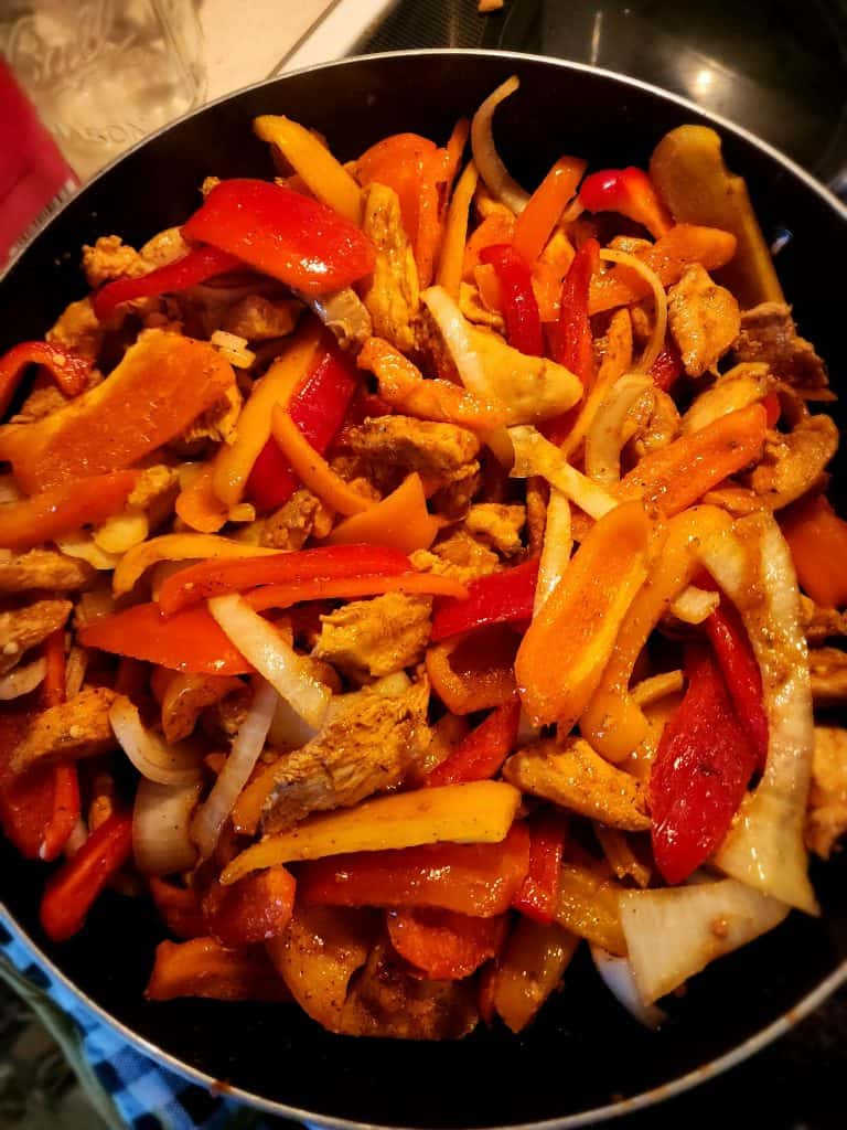 adding peppers to the chicken for fajita marinade