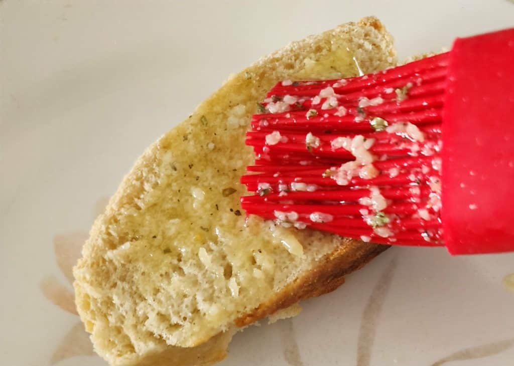 adding garlic seasoning butter to bread