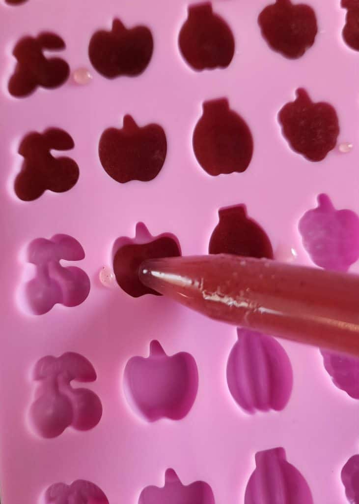 using eye dropper to add elderberry gummy mixture to gummy mold