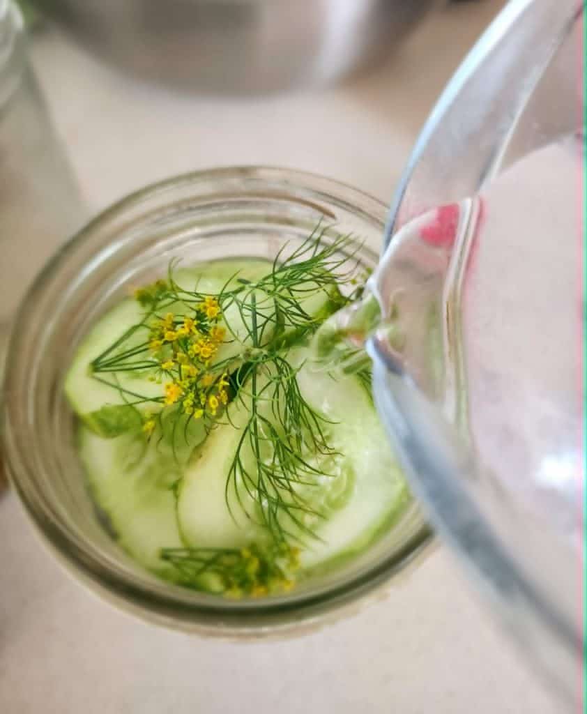 pouring brine over refrigerator pickles