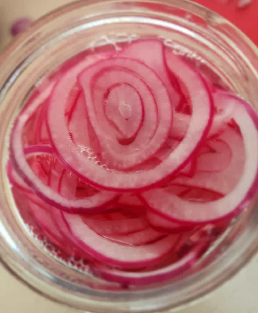 pickled red onions top of jar after pouring brine on top