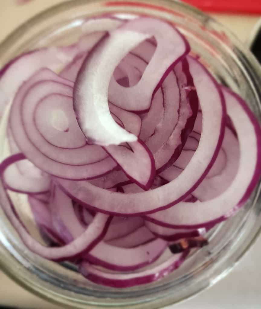 sliced red onions in jar to make pickled red onions